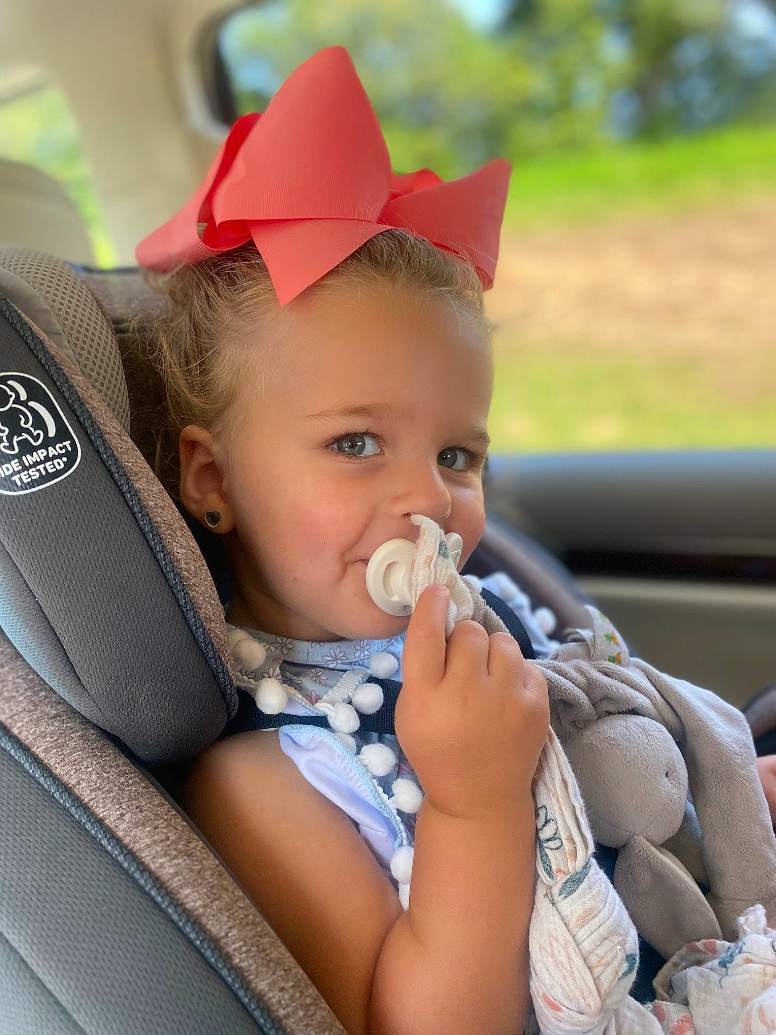 Ada Jane is registered to the contest to win money with this photo: arm, auto_part, automotive_wheel_system, baby, baby_toddler_clothing, cap, child, comfort, fashion_accessory, finger, fun, grass, happy, hat, headgear, lip, person, skin, steering_wheel, toddler