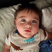 Yazan is registered to the contest to win money with this photo: baby, child, onesie, animal_print, bed, pillow, blanket, face, eyes, hair, mouth, skin, infant, cute, lying_down, indoors, portrait, soft_lighting, expression, cozy