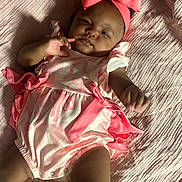 Emmalee is registered to the contest to win money with this photo: baby, infant, pink_bow, pink_outfit, blanket, lying_down, cute, face, hand, legs, portrait, child, soft_texture, indoors, clothing, person, toddler, sleepwear, fashion, adorable