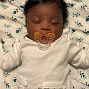 Starr is registered to the contest to win money with this photo: newborn, baby, infant, sleeping, pacifier, portrait, close_up, lying_down, onesie, white_clothing, floral_blanket, bed, indoors, dark_hair, closed_eyes, face, calm, cute, nursery, bunny_pockets