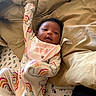 baby, infant, child, portrait, smiling, happy, lying_down, bed, bedding, pillows, blanket, onesie, rainbow_pattern, bib, clothing, face, curly_hair, indoor, cozy, photography