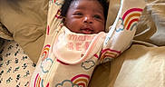 Starr joined the competition — help win amazing prizes! adorable, arms_raised, baby, baby_photography, bed, bedding, bib, close_up, clouds, face, happy, indoor, infant, lying_down, newborn, pajamas, pillows, portrait, rainbow, smiling