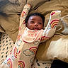 baby, newborn, infant, portrait, smiling, happy, lying_down, arms_raised, rainbow, clouds, pajamas, bib, bedding, pillows, bed, indoor, close_up, face, adorable, baby_photography