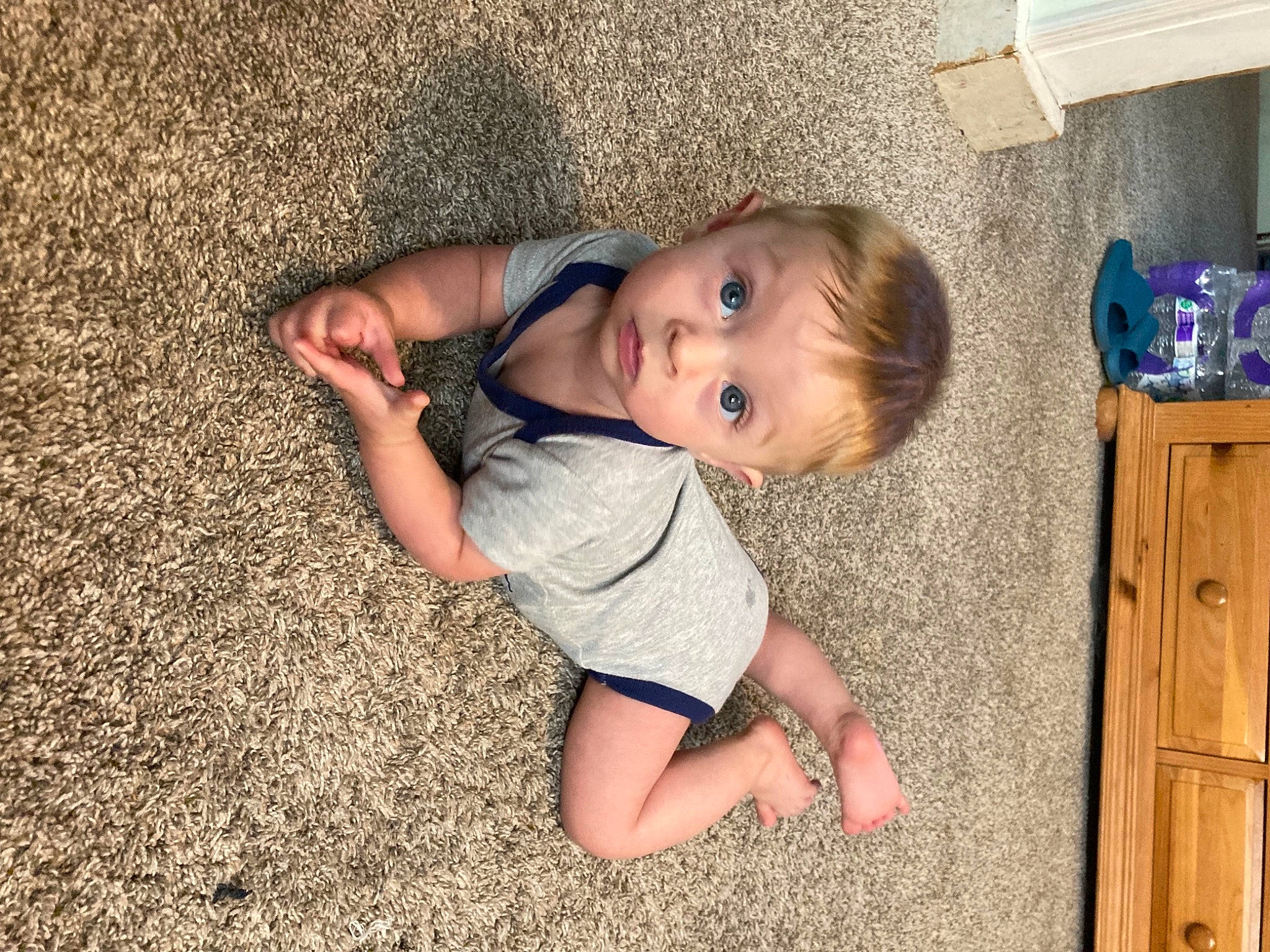 Boston is registered to the contest to win money with this photo: baby_toddler_clothing, cabinetry, cheek, child, facial_expression, finger, floor, flooring, fun, grass, happy, human, leg, mammal, mouth, nose, person, skin, surprise, toddler
