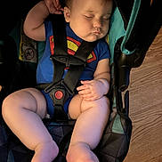 Adam is registered to the contest to win money with this photo: baby, sleeping, car_seat, blue_onesie, superman_logo, chubby_legs, infant, child, indoor, wooden_floor, safety_harness, peaceful, cute, portrait, childcare, resting, baby_fashion, toddler, seat, comfort