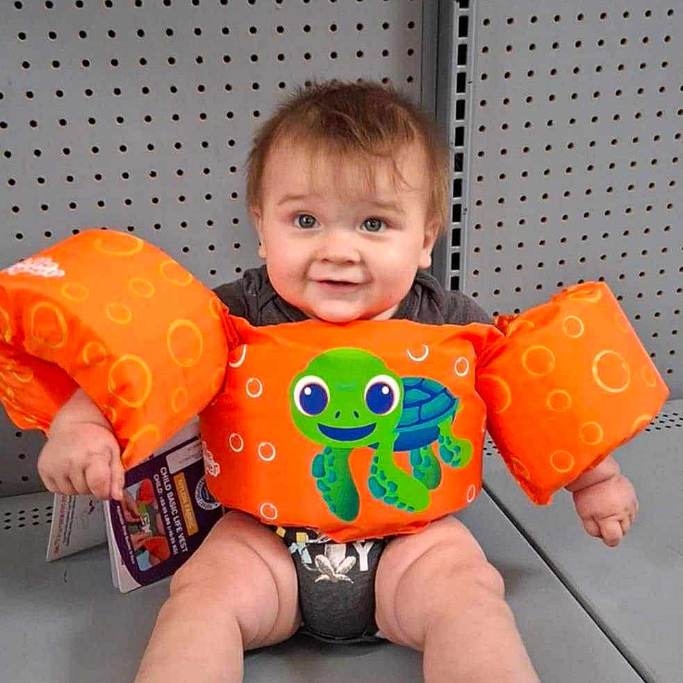 Adam joined the competition — help win amazing prizes! baby, child, clothing, cute, feet, floaties, gray, happy, indoor, infant, legs, metal, orange, pegboard, person, shelf, sitting, smiling, toy, turtle