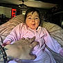 Isabella is registered to the contest to win money with this photo: baby, child, hand, tattoo, bracelet, pink_onesie, striped_clothing, smiling, tickling, cozy, indoor, blanket, cute, person, infant, face, expression, happy, playful, home