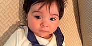 Isabella is registered to the contest to win money with this photo: baby, child, infant, face, portrait, couch, clothing, overalls, flower, earring, hair, texture, white_shirt, indoor, cute, young_child, looking, sitting, soft_lighting, expression