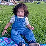child, toddler, curly_hair, portrait, sitting, outdoor, grass, lawn, picnic, blanket, colorful_blanket, blue_overalls, striped_shirt, shoes, sunset, park, folding_chairs, cars, trees, family_gathering