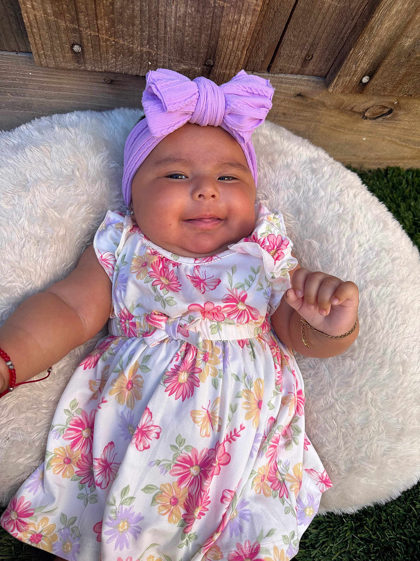 Ailaney joined the competition — help win amazing prizes! baby, child, smiling, headband, bow, floral_dress, outdoor, grass, wooden_fence, cushion, happy, portrait, infant, cute, skin, person, toddler, fashion, accessory, lying_down