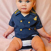 Kaston is registered to the contest to win money with this photo: baby, child, infant, sailor_shirt, blue_eyes, flower_headband, sitting, pink_blanket, cute, portrait, clothing, gold_buttons, soft_texture, indoors, skin, person, legs, hands, head, face