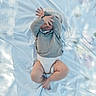 Tiago participe au concours pour gagner de l'argent avec cette photo : baby, blanket, child, clothing, cozy, cute, diaper, face_covering, fingers, hand, indoors, infant, laying_down, legs_crossed, light_blue, patterned, portrait, skin, sleeve, soft_light
