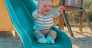 Tiago a rejoint le concours — aidez-le/la à gagner de superbes lots ! baby, blue_sky, child, clothing, cute, daylight, fun, gravel, happy, infant, outdoor, person, play, playground, recreation, sitting, slide, smiling, toy, wood