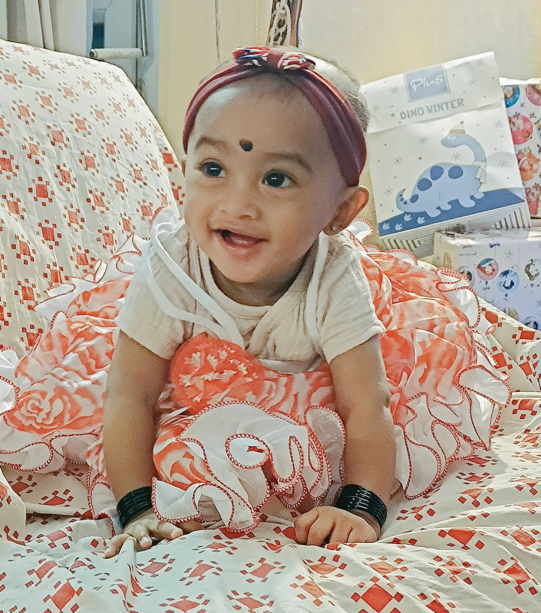 Sïa participe au concours pour gagner de l'argent avec cette photo : baby, baby_toddler_clothing, child, comfort, facial_expression, flooring, fun, hairstyle, happy, joy, linens, pattern, person, pink, red, sitting, skin, sleeve, smile, textile