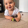 baby, child, toy_car, carpet, smiling, happy, indoors, face, hand, white_shirt, floor, crawling, cute, infant, playtime, bright, portrait, closeup, young_child, curious