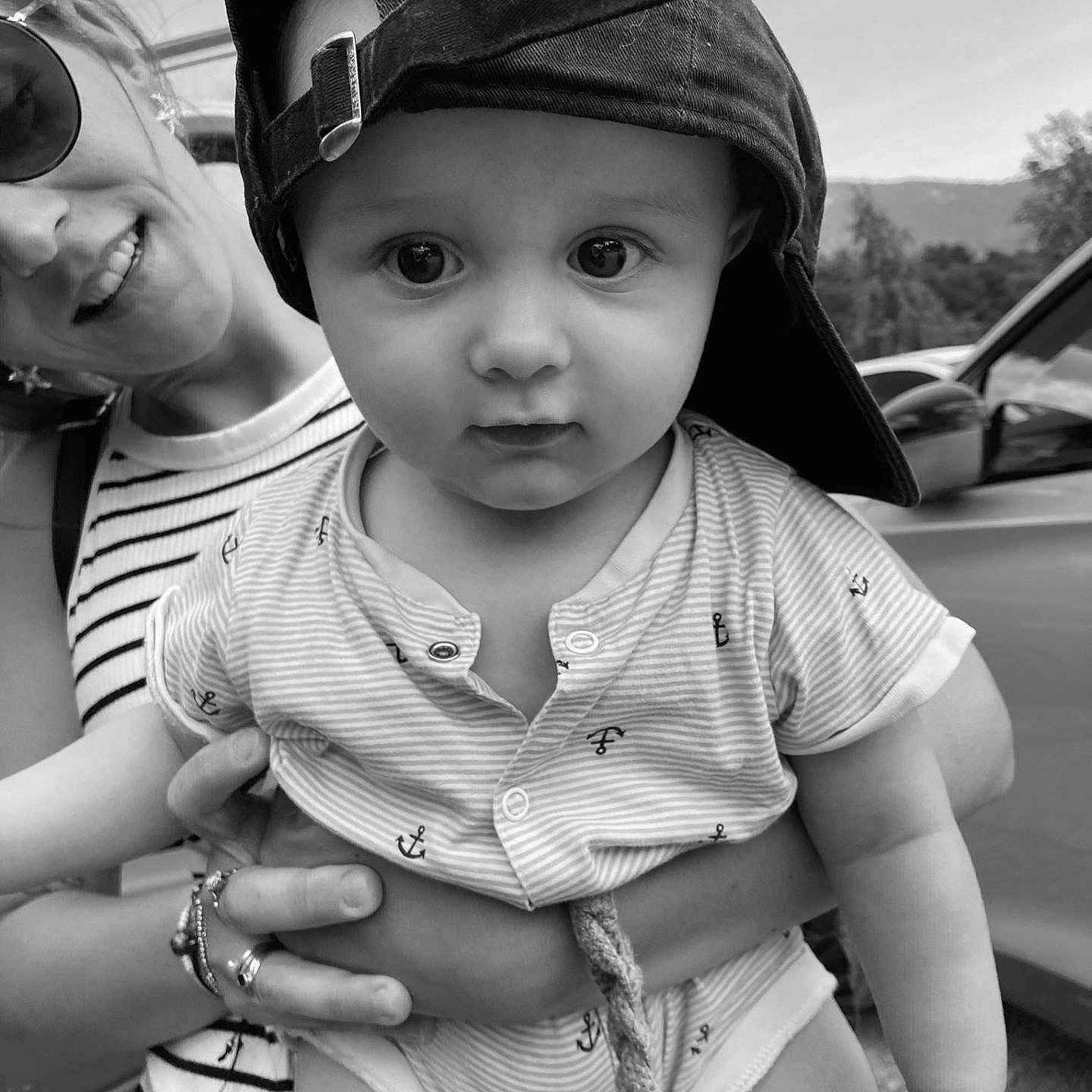 Gaëtan participe au concours pour gagner de l'argent avec cette photo : baby, black_and_white, cap, car, child, cute, face, hand, hat, holding, nature, outdoor, person, portrait, rope, smile, striped_shirt, sunglasses, woman, young_child
