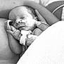 newborn, baby, sleeping, medical_tube, swaddled, black_and_white, infant, hand, adult_arm, peaceful, hospital, closeup, portrait, tender, resting, fragile, skin, blanket, care, love