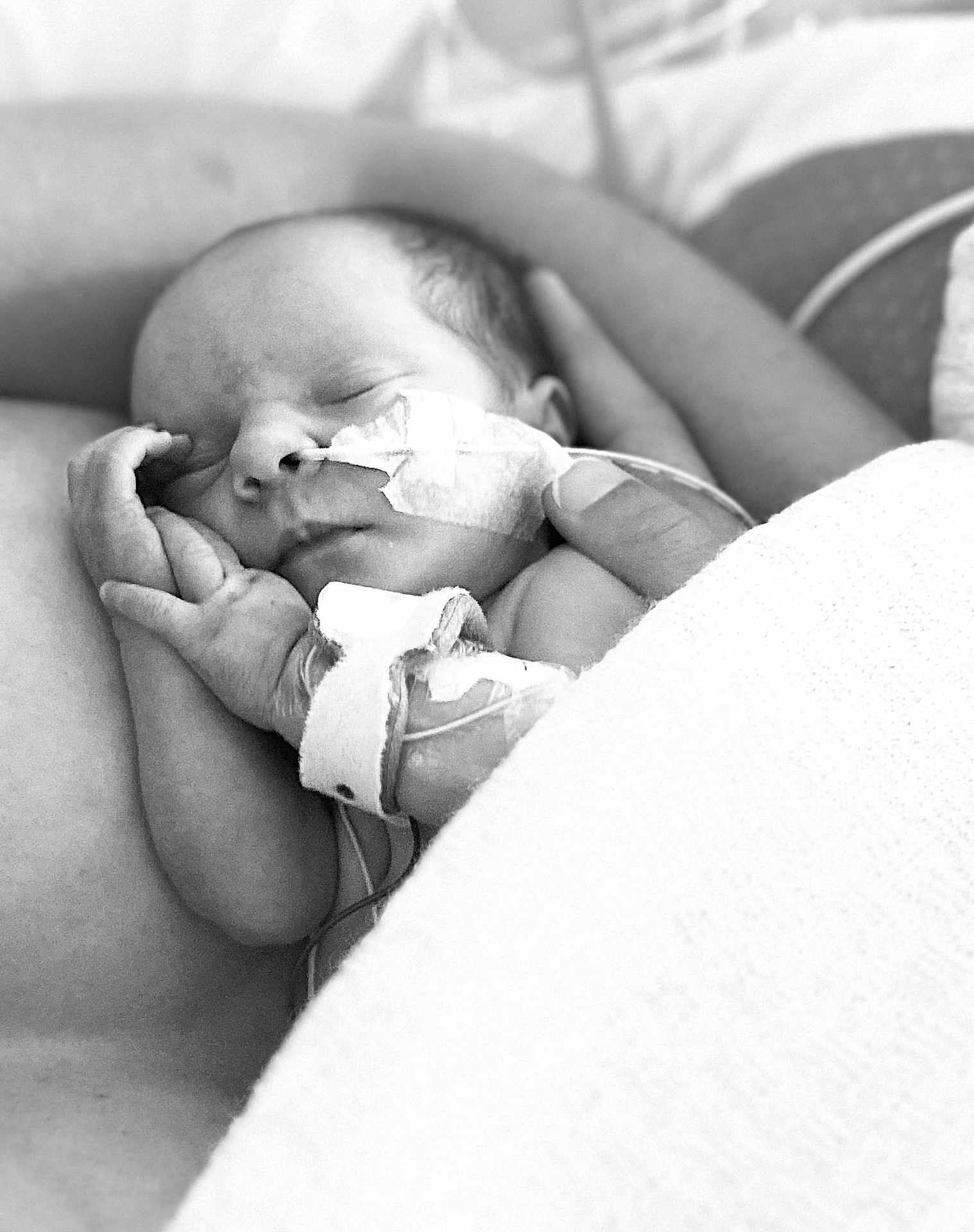 Ella participe au concours pour gagner de l'argent avec cette photo : newborn, baby, sleeping, medical_tube, swaddled, black_and_white, infant, hand, adult_arm, peaceful, hospital, closeup, portrait, tender, resting, fragile, skin, blanket, care, love