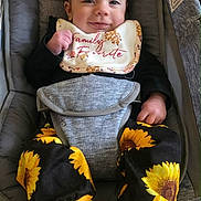 Sophia joined the competition — help win amazing prizes! baby, infant, child, smiling, happy, bib, headband, sunflower_pattern, pants, socks, car_seat, infant_carrier, harness, gray_fabric, cushion, portrait, closeup, clothing, hands, feet