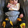 baby, infant, child, smiling, happy, bib, headband, sunflower_pattern, pants, socks, car_seat, infant_carrier, harness, gray_fabric, cushion, portrait, closeup, clothing, hands, feet