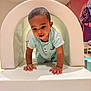 child, colorful, crawling, curious, exploration, furniture, hands, head, indoor, kid, light_blue_outfit, mural, person, play, playroom, smiling, soft_play, toddler, white_tunnel, young_child