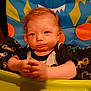 baby, child, high_chair, colorful, monster_design, food, hands, face, expression, indoor, clothing, blanket, seat, person, cute, infant, orange, blue, green, yellow