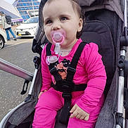 Emma Ridajova is registered to the contest to win money with this photo: baby, child, stroller, pacifier, pink_clothing, bow, urban, street, car, pedestrian, face, infant, outdoor, cute, sitting, young_child, daylight, casual, people, transportation