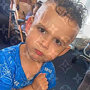 Alex Ridaj is registered to the contest to win money with this photo: child, boy, curly_hair, blue_shirt, serious_expression, indoor, furniture, background_child, pattern_overlay, portrait, close_up, face, young_child, casual_clothing, home, person, expression, sitting, room, hair