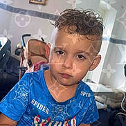 Alex Ridaj is registered to the contest to win money with this photo: child, boy, indoor, blue_shirt, spider_design, short_hair, serious_expression, stroller, framed_picture, wall, window, furniture, carpet, hand, sitting, portrait, pattern_overlay, logo, casual_clothing, young