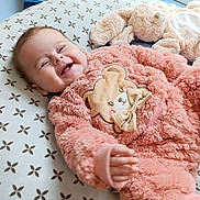 Elena participe au concours pour gagner de l'argent avec cette photo : baby, child, cozy, cushion, cute, face, happy, head, indoor, infant, light, onesie, patterned_bedding, pink_clothing, plush_toy, reaching_hand, smiling, soft_texture, stuffed_animal, window