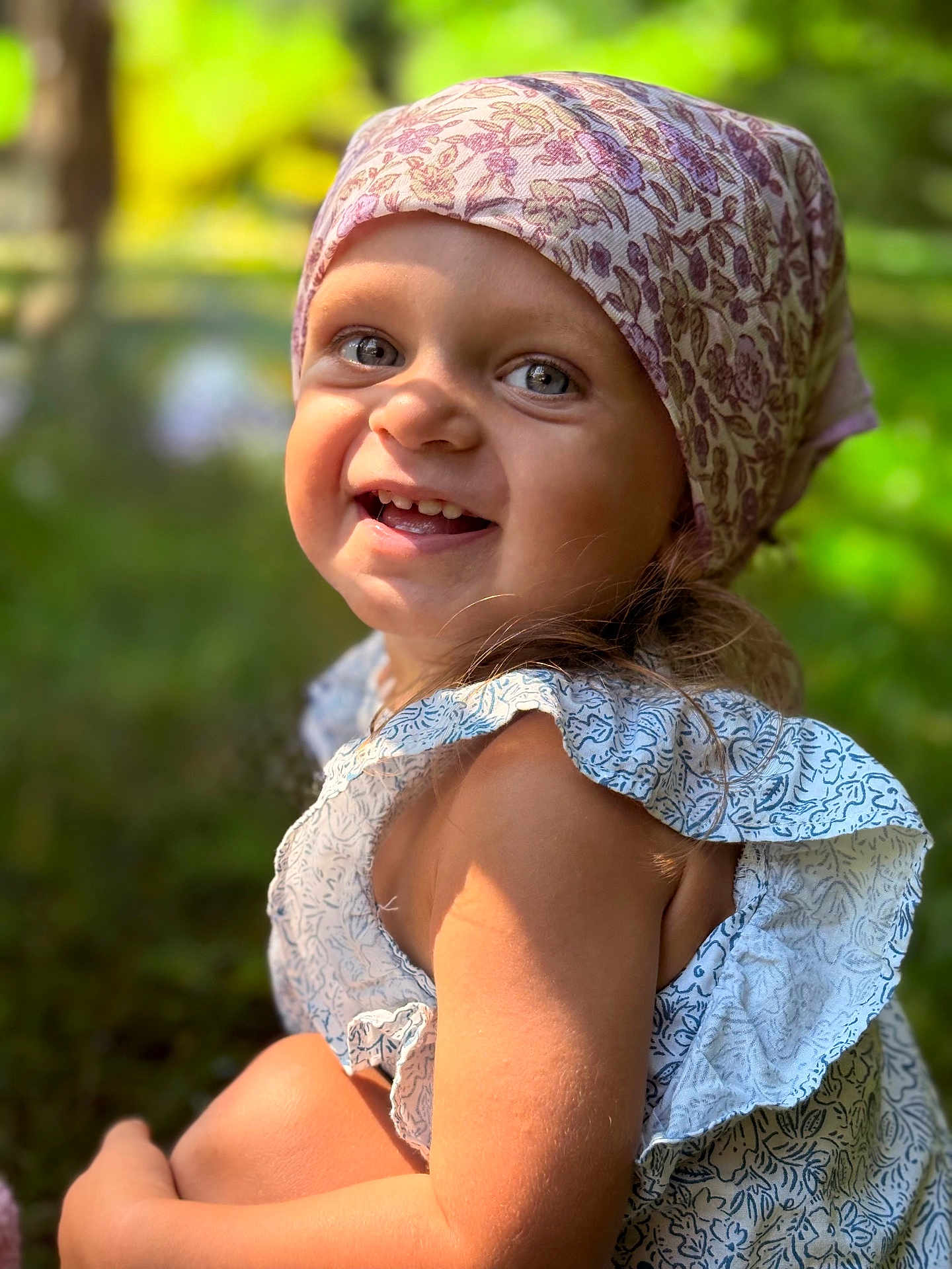 Eléa participe au concours pour gagner de l'argent avec cette photo : child, toddler, smiling, headscarf, outdoor, sunlight, portrait, happy, face, blue_eyes, floral_pattern, dress, nature, greenery, cute, skin, person, summer, closeup, young