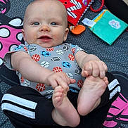 Robert Michels joined the competition — help win amazing prizes! baby, child, infant, smiling, portrait, lying_down, indoor, play_mat, toys, colorful, football, sports_pattern, onesie, bare_feet, toes, hands, blue_eyes, happy, close_up, family_photo