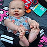 baby, child, infant, smiling, portrait, lying_down, indoor, play_mat, toys, colorful, football, sports_pattern, onesie, bare_feet, toes, hands, blue_eyes, happy, close_up, family_photo