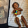 Sekani joined the competition — help win amazing prizes! baby, infant, diaper, rattle, playpen, mattress, pattern, curly_hair, child, indoor, toy, lying_down, expression, skin, hand, foot, face, mouth_open, wide_eyes, mesh
