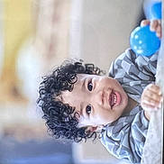 Junaid joined the competition — help win amazing prizes! child, toddler, curly_hair, smiling, blue_ball, indoor, person, happy, face, clothing, playful, portrait, closeup, baby, cute, hands, expression, young, leisure, fun