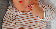 Raayan a rejoint le concours — aidez-le/la à gagner de superbes lots ! baby, blanket, brown_pants, child, clothing, cozy, cute, expression, face, fingers, hand, heart_stickers, indoors, infant, lying_down, person, portrait, skin, striped_shirt, young