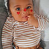 baby, blanket, brown_pants, child, clothing, cozy, cute, expression, face, fingers, hand, heart_stickers, indoors, infant, lying_down, person, portrait, skin, striped_shirt, young