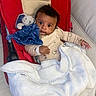 baby, blanket, blue_toy, child, clothing, comfort, cozy, cute, expression, face, indoor, infant, person, plush_toy, portrait, red_baby_seat, resting, soft, wide_eyes, young