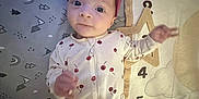 Rayna is registered to the contest to win money with this photo: baby, child, infant, onesie, headband, crib, bedding, pattern, cherry, purple, numbers, soft, cute, sleepwear, playful, curious, lying_down, indoors, person, young_child