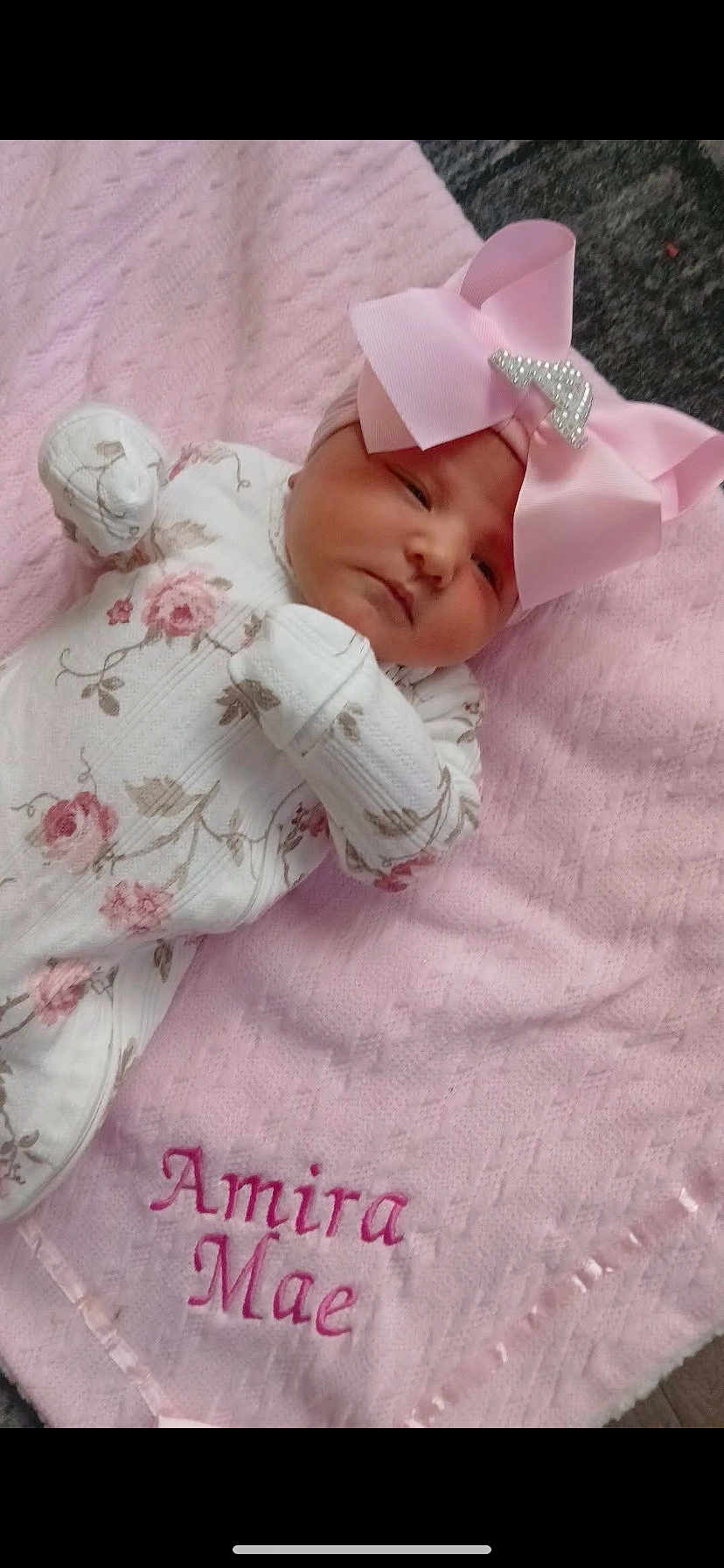 Amira Mae is registered to the contest to win money with this photo: baby, newborn, infant, pink_bow, floral_onesie, blanket, embroidered_text, soft_texture, resting, cute, sleepy, indoor, child, portrait, headband, pink, white, cozy, peaceful, baby_clothes