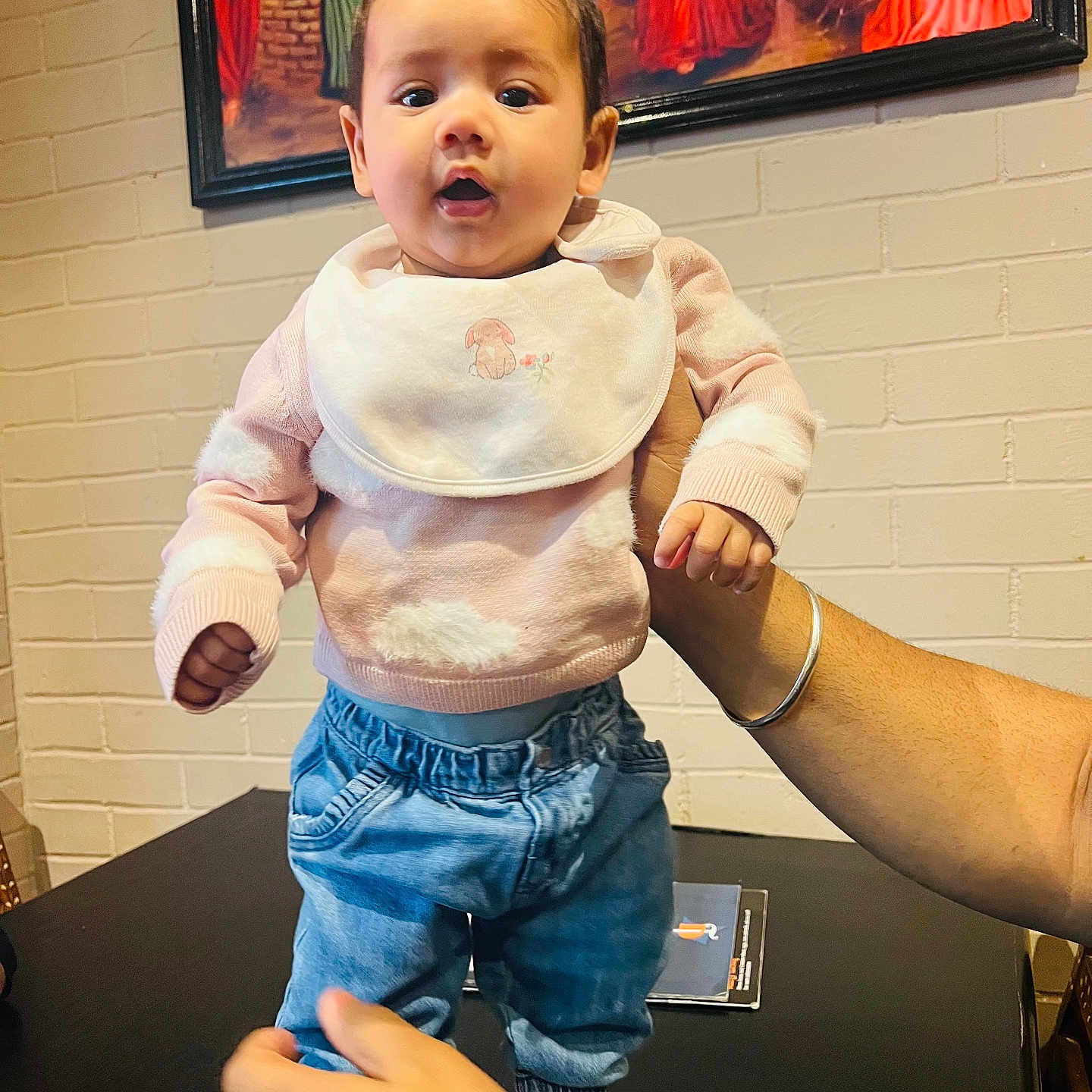 Seerat joined the competition — help win amazing prizes! baby, blue_jeans, bracelet, brick_wall, casual_clothing, child, curious, cute, expression, hands, holding, indoor, painting, pants, person, portrait, sock, sweater, table, watch