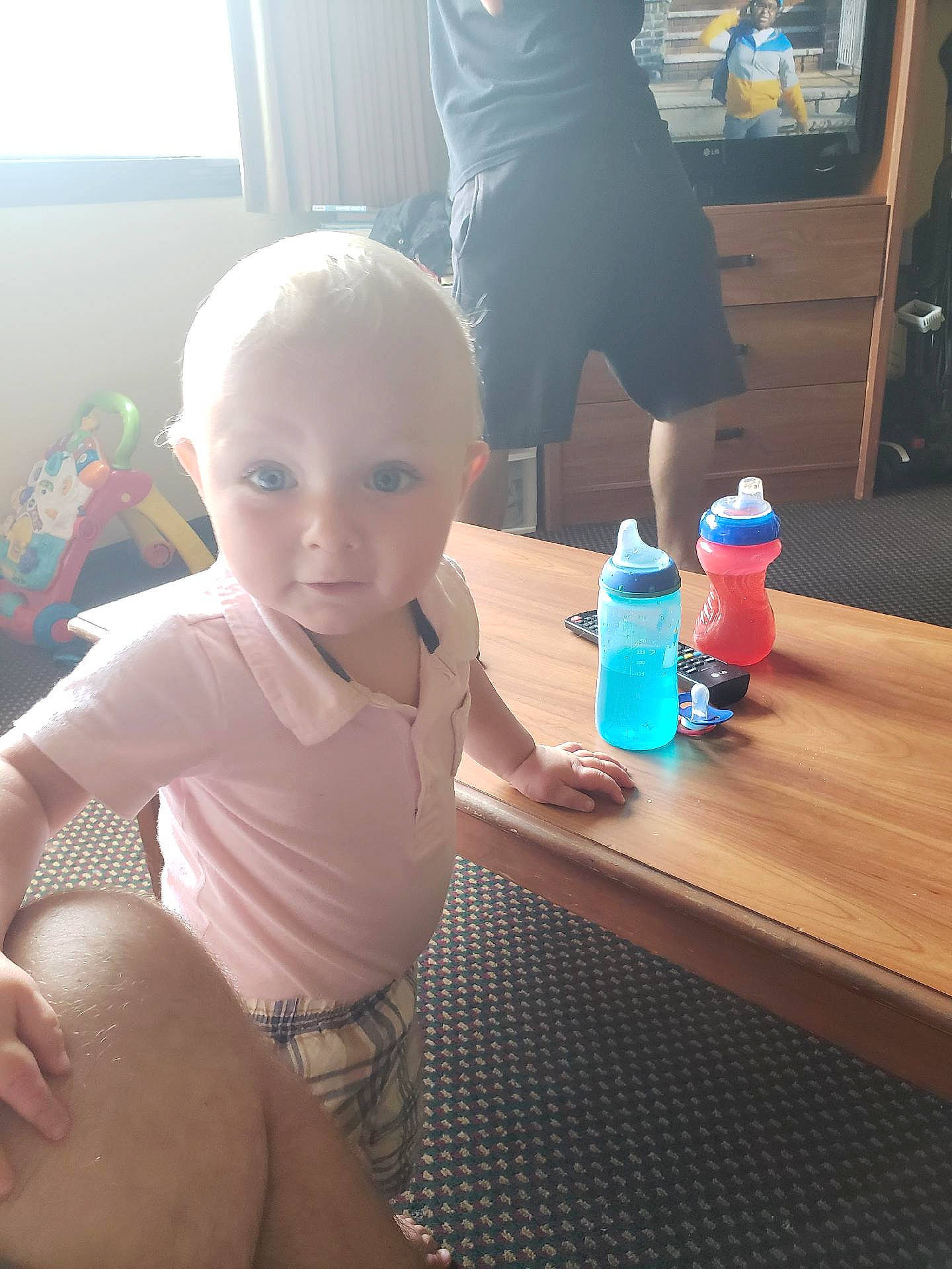 Bailey is registered to the contest to win money with this photo: arm, bottle, facial_expression, finger, hairstyle, hand, human_body, joint, leg, mouth, muscle, person, plastic_bottle, shorts, shoulder, skin, standing, table, thigh, water_bottle