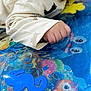 baby, hand, fist, sleeve, clothing, play_mat, colorful, sea_creatures, water_bubbles, blue, yellow, pink, orange, green, infant, cute, pattern, soft_fabric, closeup, child
