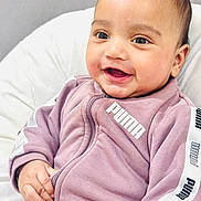 Bramh joined the competition — help win amazing prizes! baby, child, smile, face, puma, tracksuit, purple_clothing, happy, indoor, cushion, hand, sitting, young_child, portrait, cute, apparel, infant, fashion, casual_wear, closeup