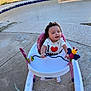 baby, baby_walker, child, clothing, concrete, empty_pool, grass, happy, heart, outdoor, person, pink, playful, pool, shirt, sidewalk, smiling, sunlight, toy, white