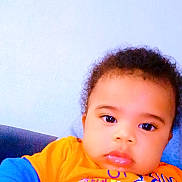 émile-Lamine a rejoint le concours — aidez-le/la à gagner de superbes lots ! toddler, child, baby, face, portrait, blue_clothing, orange_clothing, indoor, couch, expression, curly_hair, skin, person, young_child, casual_wear, looking_at_camera, sitting, closeup, text_overlay, emoji