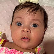 Zoe joined the competition — help win amazing prizes! baby, child, face, eyes, bow, pink, cushion, clothing, portrait, expression, cute, infant, closeup, headwear, person, young, skin, surprise, soft, indoors
