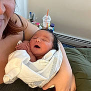 James joined the competition — help win amazing prizes! newborn, baby, blanket, wrapped, sleeping, adult, hand, arm, indoor, bedroom, cozy, person, smile, ring, hair, face, clothing, furniture, table, drink