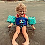 Willow joined the competition — help win amazing prizes! child, toddler, beach, sand, water, floaties, swimsuit, curly_hair, playing, outdoor, smiling, barefoot, summer, fun, vacation, building, cloudy_sky, sand_play, happy, coast