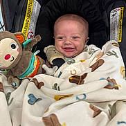 Bennett joined the competition — help win amazing prizes! baby, smile, car_seat, blanket, toy, pacifier, monkey_toy, infant, child, happy, face, clothing, cute, sitting, indoor, safety_warning, fabric, head, comfort, blanket_pattern